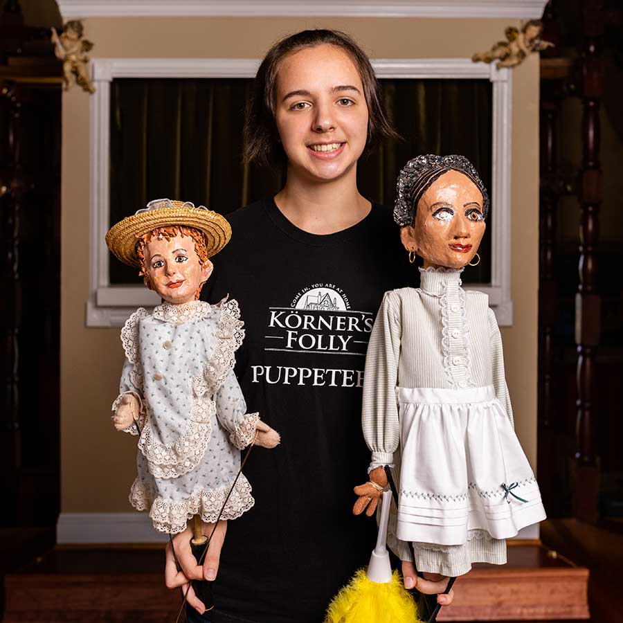 Lindsey Hart in black shirt holding two puppets.